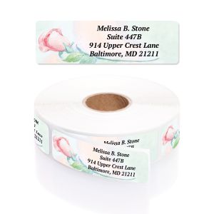A rectangular personalized address label displayed above a large roll of matching labels, featuring a delicate pink and pastel watercolor rose design.