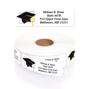 A rectangular personalized graduation address label displayed above a large roll of matching labels, featuring a classic black mortarboard cap.