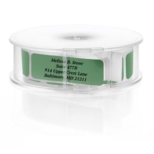 A roll of personalized green foil address labels displaying elegant black typography for the name and address lines on a white background.