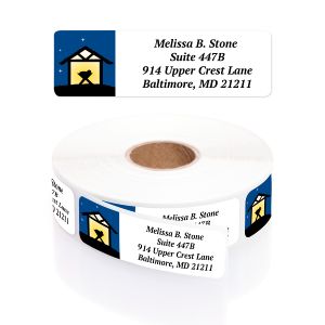 A roll of Christmas address labels featuring a dark blue nativity scene with a golden manger illustration and clean four-line typography layout.