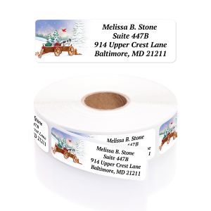 A roll of personalized Creature Comforts address labels featuring pets in a wagon with Christmas gifts and custom return address text.