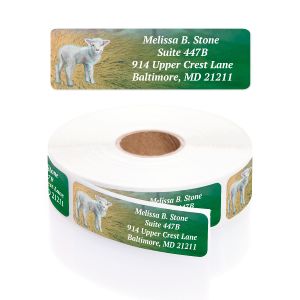 A paper roll of A True Miracle address labels featuring an illustration of a white lamb in a meadow beside a vibrant green text layout block.