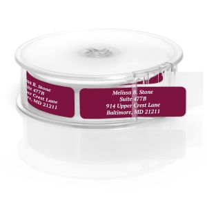 A roll of personalized address labels showcasing a vibrant, solid plum purple background with crisp white text, housed in a clear plastic dispenser.