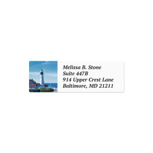 A rectangular personalized address label showcasing a scenic coastal illustration of a white lighthouse next to the ocean with custom text.