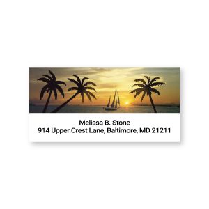 A close-up of a rectangular address label showcasing a warm tropical sunset scene with palm trees, a sailboat, and elegant custom text.