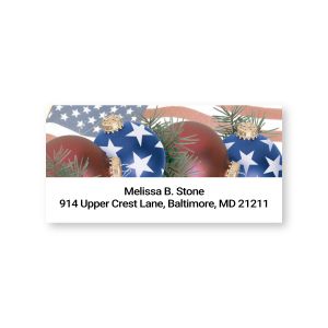 Rectangular patriotic address label featuring red holiday ornaments, pine greenery, and an American flag pattern above two lines of custom text.