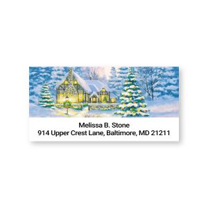 Rectangular address label featuring a snowy country cottage illustration above two lines of customizable return name and address text.