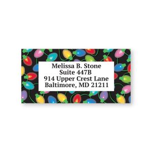Close-up view of a personalized address label featuring colorful festive holiday light bulbs bordering customizable name and return address text.