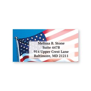 Single sheeted address label featuring a fluttering American flag background design with sample personalized name and return address text.