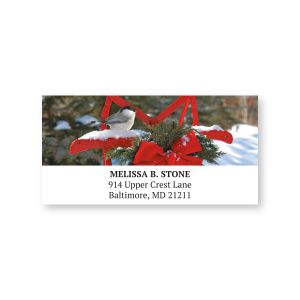 Personalized holiday address label featuring a small bird perched on a red sled with evergreen greenery above custom return address lines.