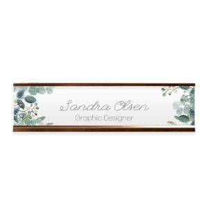 Personalized floral greenery desk plate in a rose gold metal holder displaying custom name and professional title on a white backdrop.