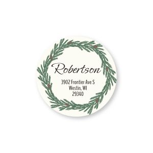 Round customized return address label featuring a sketched pine Christmas wreath illustration with red berries surrounding personalized text.