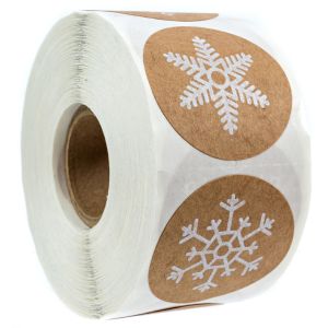 Close-up of a roll of brown kraft paper stickers featuring white printed snowflake designs, highlighting two round labels on the front of the roll.