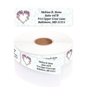 A large roll of white address labels featuring an elegant purple and green watercolor floral heart wreath alongside clean typography layout.