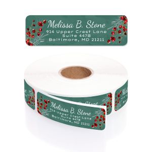 A rectangular personalized address label displayed above a large roll of matching labels, showcasing a festive green pine and red berry motif.
