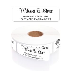 A large roll of white address labels featuring personalized black print in an elegant cursive script name and clean block text.