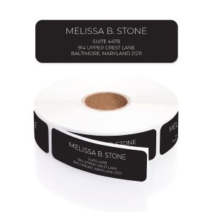 A roll of personalized black address labels featuring clean white typography for the name and address lines on a solid white background.