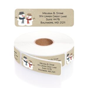 Kraft paper return address label with two winter snowmen displayed next to a roll of matching labels.
