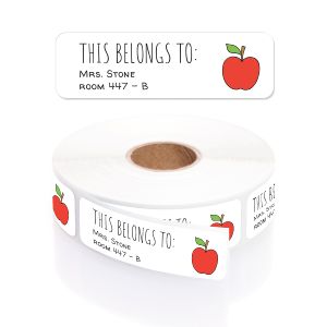 A roll of personalized classroom labels featuring a red apple design, sitting inside a clear, round plastic dispenser on a plain background.