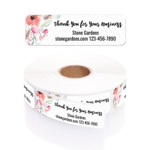 A roll of white rectangular business labels with pink floral accents and custom text, showing continuous labels wrapped around a central core.