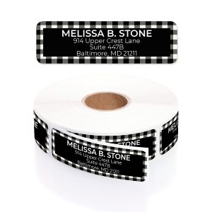 A paper roll of Buffalo Plaid address labels showcasing a bold black and white checkered border pattern beside a clean typography layout template.
