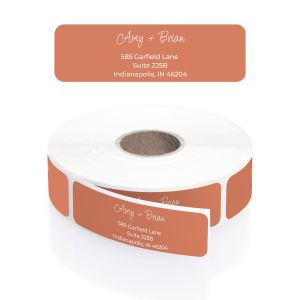A rectangular personalized address label displayed above a large roll of matching labels, showcasing a solid, modern burnt orange background.