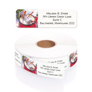 Single personalized address label featuring a marshmallow snowman in a mug displayed above a rolled coil of printed stickers.