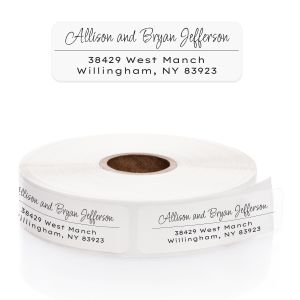 A roll of personalized clear address labels showcasing a delicate black script font for names and a clean, legible serif address font.