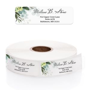 A close-up of a roll of clear address labels featuring a lush green watercolor foliage and white flower design alongside clean, elegant text.