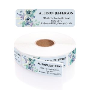 A rectangular personalized address label displayed above a large roll of matching labels, featuring a delicate blue and purple watercolor floral design.