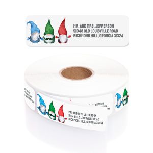 A rectangular personalized address label displayed above a large roll of matching labels, featuring three festive watercolor gnomes.