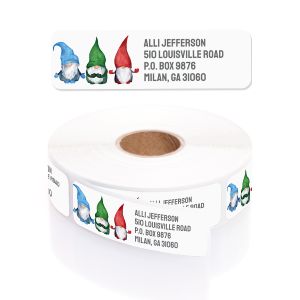 A rectangular personalized address label displayed above a large roll of matching labels, featuring three festive watercolor gnomes.